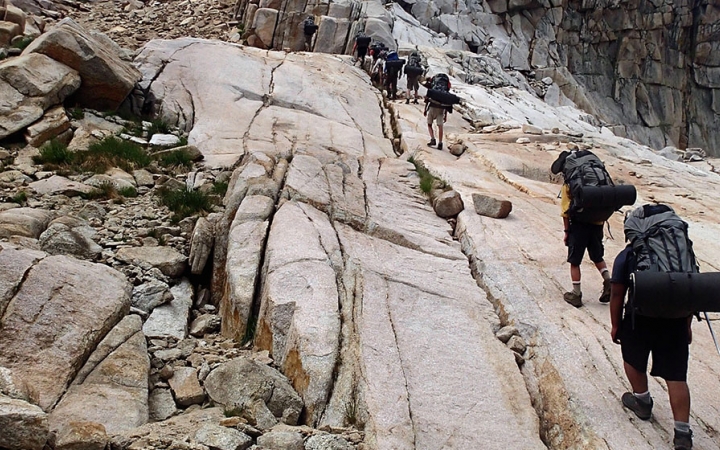 a group of backpackers hike up a rocky incline 