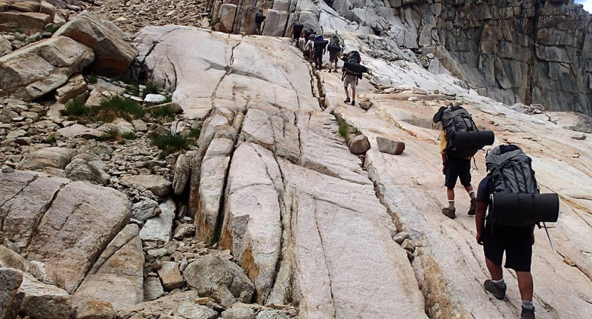 a group of backpackers hike up a rocky incline 